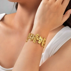 Macro detail of golden irregular wavy textured wide cuff bracelet with polished finish