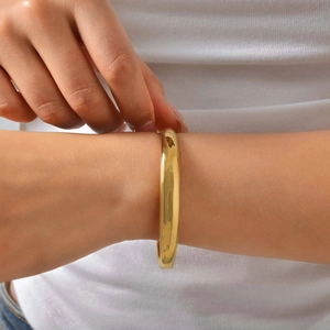 Minimalist 18K gold plated stainless steel bangle with polished mirror finish on a model
