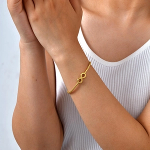 Close-up of infinity symbol on gold-plated stainless steel twisted open bangle