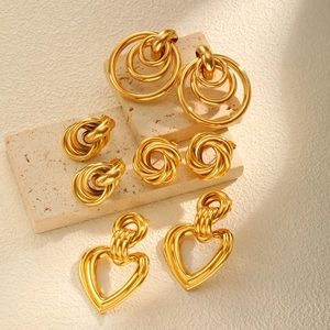 Elegantes Set aus goldenen Herz- und geometrischen Ohrringen auf Steindekor