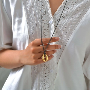 Minimalist gold oval fish scale pendant on a long black adjustable cord necklace for women