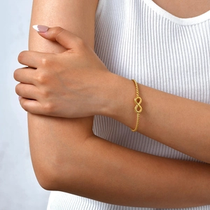 Polished 18K gold plated infinity rope open bangle bracelet worn on a model wrist