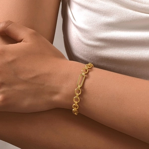 Close-up of golden Figaro cross chain bracelet with polished rectangular links on wrist