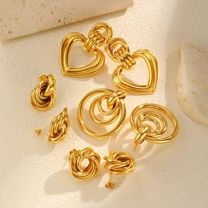 Set aus goldenen Herz- und geometrischen Ringohrringen auf Naturstein-Hintergrund