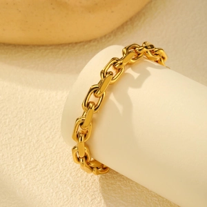 Chunky 18K gold-plated stainless steel link bracelet on a white cylindrical display stand