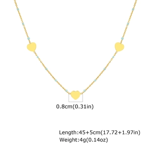 Détail de cœurs dorés et perles bleues sur un collier à plat en acier inoxydable