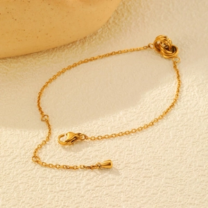 Détail d'un bracelet doré en acier inoxydable avec triple anneaux entrelacés et fermoir mousqueton