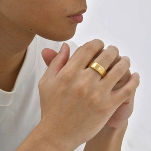 Gros plan d'une bague pour homme en acier doré brossé avec sertissage d'un diamant