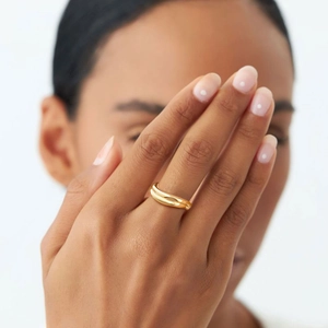 Close-up of a double-layered 18K gold plated stainless steel wave ring on a model hand