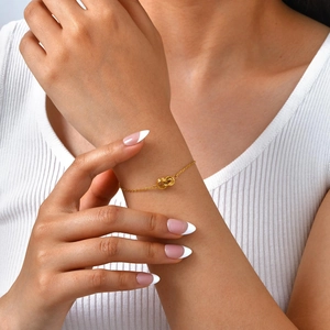 Gros plan d'un bracelet doré à doubles anneaux entrelacés sur un poignet féminin