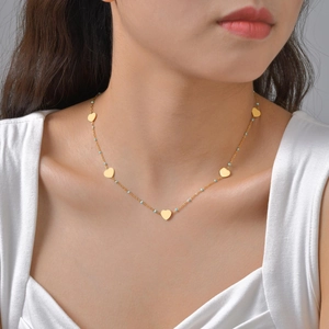 Collier doré avec pendentifs en forme de cœur et perles bleues porté par un mannequin