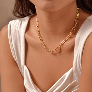 Detail of a textured gold paperclip chain necklace worn on a model in white silk