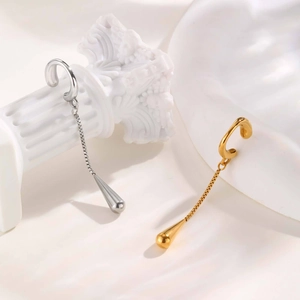 Detail of silver and gold long chain teardrop ear cuffs on a white Roman column
