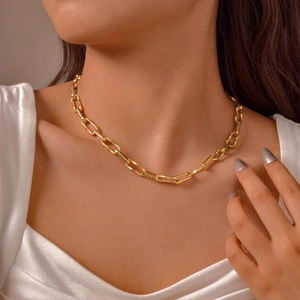 Macro detail of gold-tone rectangular chain links with textured embossed metal finish
