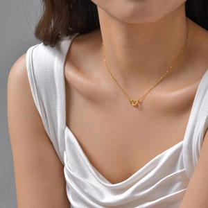 Minimalist gold intertwined heart pendant necklace shown on a model with a twisted metal design
