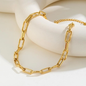 Close-up of golden paperclip chain necklace with alternating smooth and textured links