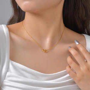 Close-up of a gold double-ring interlocking pendant necklace worn on a woman's neck