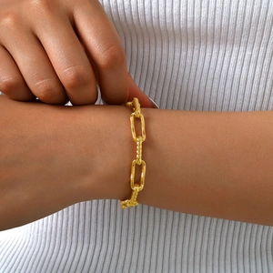 Close-up of gold stainless steel rectangular link bracelet with diamond-cut texture on wrist