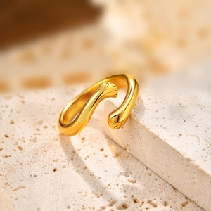 Detail shot of golden cat paw open ring with hug design on textured stone surface