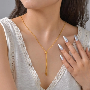 Gros plan d'un collier en Y doré avec perles et pendentifs pointus sur mannequin