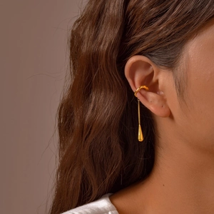 Detail of gold ear cuff with teardrop pendant and delicate chain on model ear