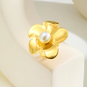 Vue détaillée d'une bague fleur dorée avec perle lustrée sur un support en pierre