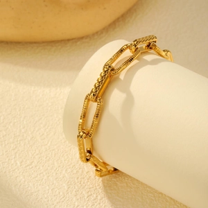 Detail of gold rectangular link chain with diamond-cut texture on a display stand