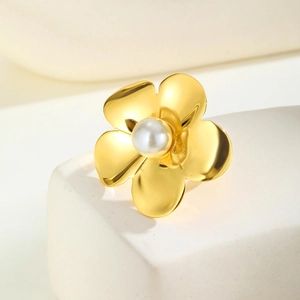 Vue macro d'une bague fleur dorée avec une perle blanche sur un socle en pierre