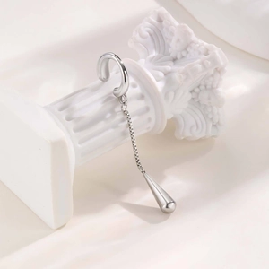 Silver ear cuff with long chain and sleek teardrop pendant on minimalist Greek column
