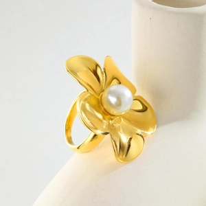 Bague fleur dorée élégante avec perle blanche sur un support en céramique minimaliste