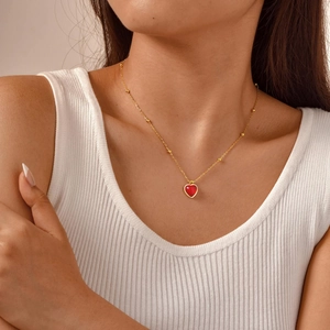 Exquis collier à billes dorées avec pendentif cœur en résine rouge sur mannequin
