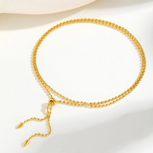 Détail du collier à perles de riz dorées avec fermoir ajustable et charms coniques