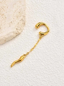 Detailed macro view of a gold-plated ear cuff with a dangling chili horn pendant and chain