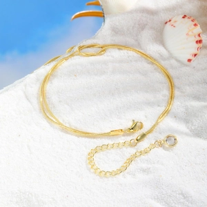 Golden snake chain anklet on white sand with sea shell for summer beach vacation style
