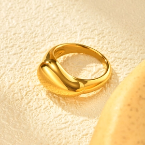 Detailed view of polished 18K gold teardrop ring on minimalist textured surface