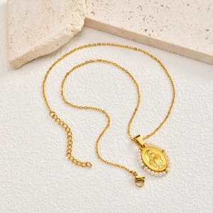 Macro detail of golden Virgin Mary oval pendant with white bead trim and O-chain links