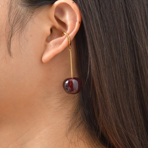 Detailed close-up of a gold cherry-shaped ear cuff with a translucent red pendant