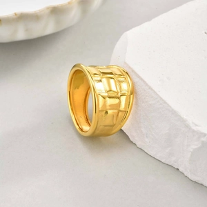 Gros plan sur une bague large plaquée or 18K avec texture tressée et motif en damier