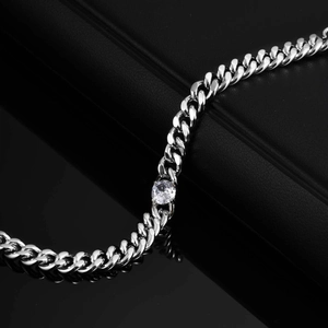 Close-up of polished stainless steel Cuban chain bracelet with central white zircon stone