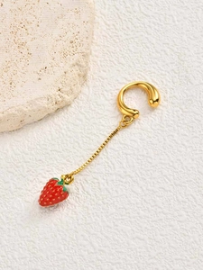 Detailed view of a gold strawberry ear cuff with a red charm and box chain on stone