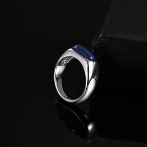 Macro shot of silver stainless steel ring with flat lapis lazuli stone on dark background