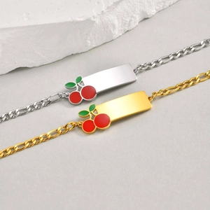 Detail of gold and silver kids' bracelets with engravable plates and cherry charms