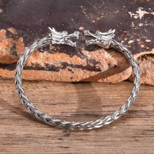 Dettaglio ravvicinato delle teste di drago su un bracciale a polsino intrecciato