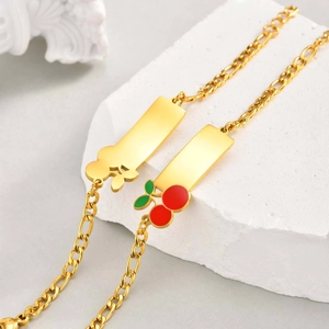 Detail of gold-plated Figaro chain bracelets with cherry enamel and floral pendants