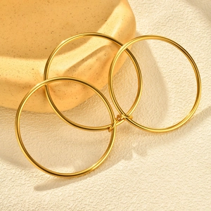 Close-up of three interlocking golden stainless steel bangles with polished finish