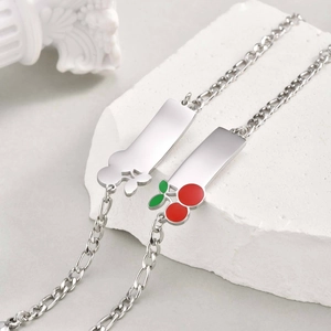 Detailed macro view of silver Figaro chain bracelet with cherry charm and cloud ID plate