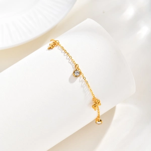 Détail du bracelet papillon doré 18K avec zircon serti sur un support blanc élégant