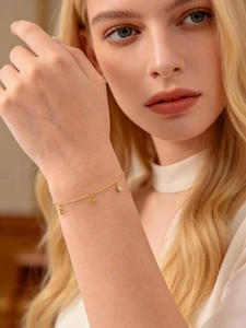 Détail du bracelet en or 18K avec perles et breloques en zircone brillante sur le poignet