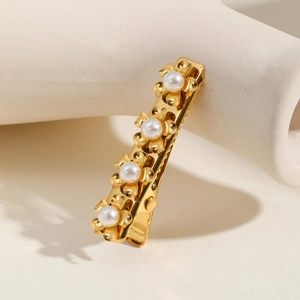 Detailed view of golden flower hair clip with white faux pearls on ceramic stand