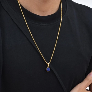 Gouden ketting met driehoekige blauwe stenen hanger gedragen op een zwart t-shirt